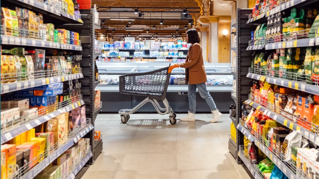 Woman pushing a shopping cart in a grocery store.